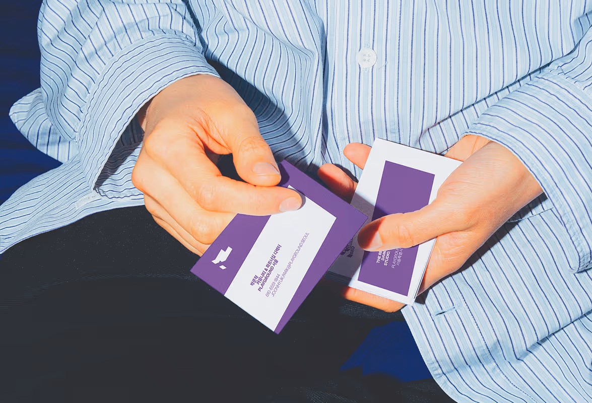Close up of hands holding their purple and white SEOUL business cards. Source : Mockup Maison