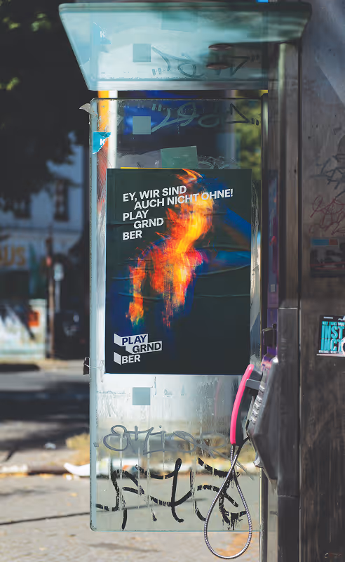 Berlin-based street poster on a public telephone station. Tagline saying " Ey, wir sind auch nicht ohne! Play Grnd Ber" (Hey we're not too bad at this) Source : Mockup Maison
