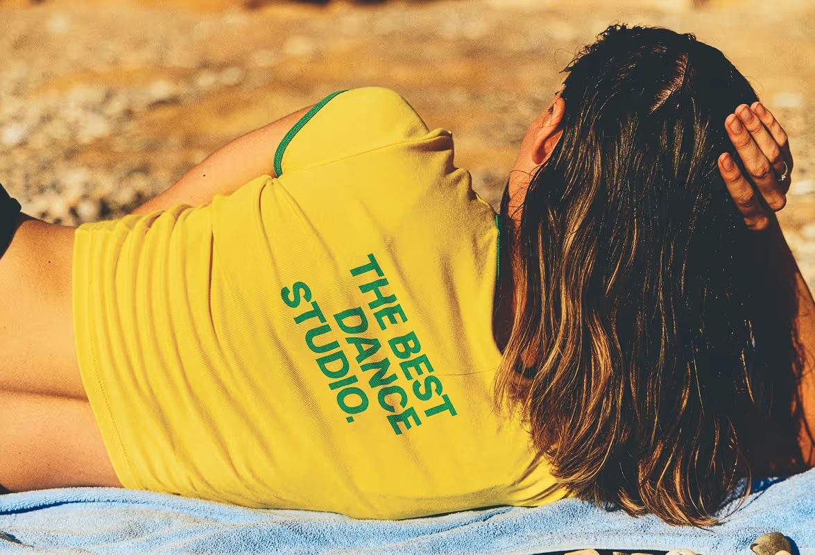 Edited picture of a woman's yellow and green t-shirt with added branded tagline saying "the best dance studio." Found on Death to Stock "my own summer" shot by Daniel Farò